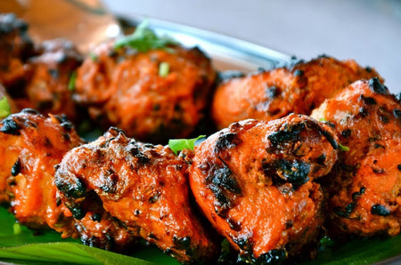 Close-up of skewered grilled meat with charred marks on a green plate.