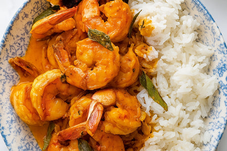 Shrimp curry with white rice on a blue and white patterned plate